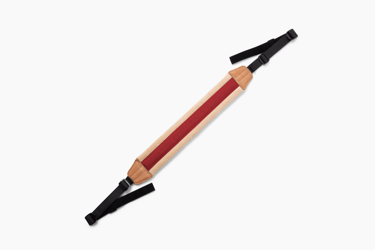 A wooden walking stick with a natural wood shaft, a red center stripe, and black adjustable straps at both ends, shown on a plain white background.